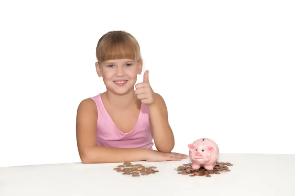 Fille avec les pouces vers le haut geste et tirelire sur la table isoler — Photo