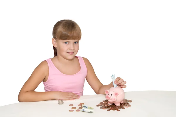 Krásná dívka dát peníze v izolované prasátko — Stock fotografie