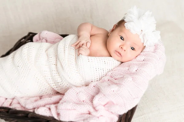 Newborn baby  with white headband laying in the basket — Stock Photo, Image