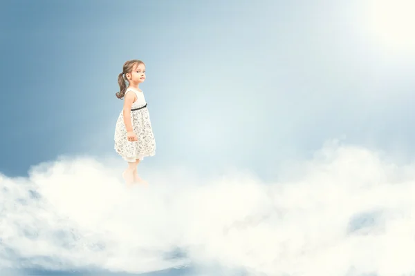 Cute little girl standing barefoot on clouds — Stockfoto