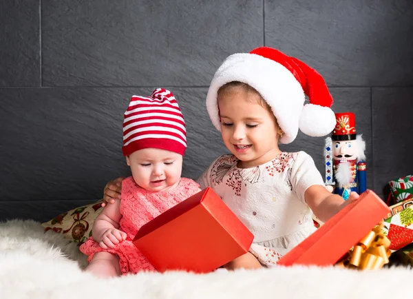 Crianças bonitos no tapete abrindo um presente de Natal — Fotografia de Stock