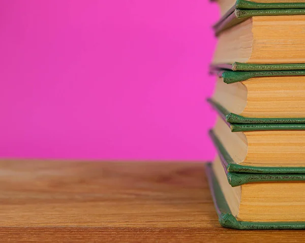 本の山がありピンクの背景にオークのテーブルの表面がある デザインの背景 — ストック写真