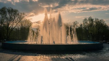Akşamları şehir parkındaki çeşme. Bahar sezonu. Web pankartı.