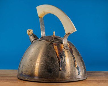 Eski yanmış çaydanlık, bir meşe ağacının üzerinde, mavi arka planda duruyor. Tasarım için.