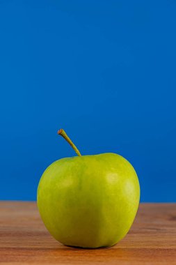 Yeşil elma, mavi arka plandaki bir meşe ağacının üzerinde duruyor. Tasarım için arkaplan.