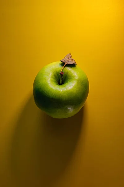 Manzana Verde Con Una Hoja Seca Encuentra Sobre Fondo Amarillo — Foto de Stock