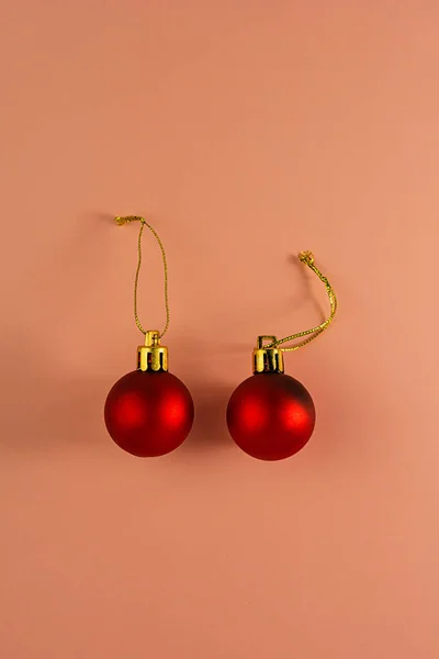 pair of Christmas red balls with a gold rope on a pink background. Festive background.