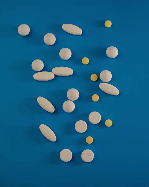 Different medical pills lie on a blue background. Medical concept.