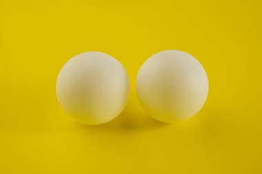 Sarı renkli arka planda iki beyaz tenis topu yatıyor. Tasarım için arkaplan.