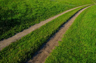 Kuru toprak yol ve yamaçtaki yeşil çimenler, kırsal alan. Yaz mevsimi, Temmuz. Ukrayna. Avrupa. Web pankartı.