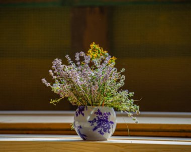 Odada, yerde duran vazoda bir buket kır çiçeği. Yaz mevsimi.