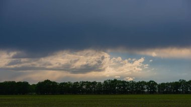 Yağmur bulutları yaprak döken ormanları, yeşil alanları, panoramik manzaraları sarıyor. Bahar mevsimi, Mayıs. Web pankartı.