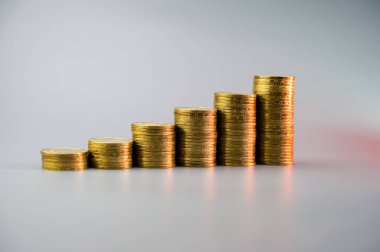 Açık gri arkaplanda yükselen altın sikke yığınları. İş konsepti.