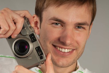 young man with a camera in his hands smiles and looks at the camera, close-up. Web banner.