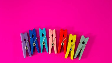 Many colorful clothespins on a pink background. Web banner.