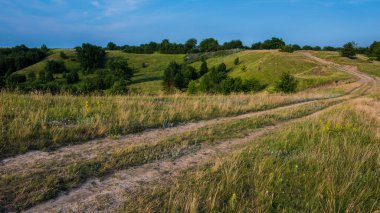 Dağlık bir bölgede toprak yol, panoramik kırsal alan. Yaz mevsimi, Haziran, Ukrayna. Avrupa. Web pankartı.