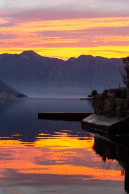Sahilde gün batımının resimli görüntüsü ve dağ arkası.