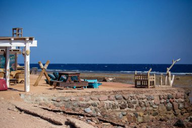 Dahab körfezi manzarası, kumsal boyunca masaları ve sandalyeleri olan açık kafe, Sina, Mısır