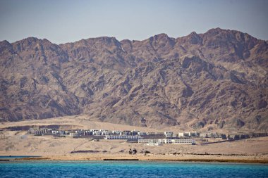 Arka planda terk edilmiş dağların olduğu deniz manzarası