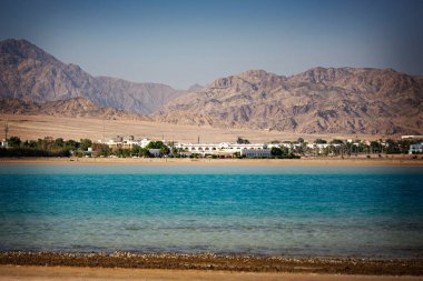 Arka planda terk edilmiş dağların olduğu deniz manzarası