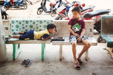 Taylandlı çocuklar Bangkok, Tayland 'da tabletle oynuyorlar.