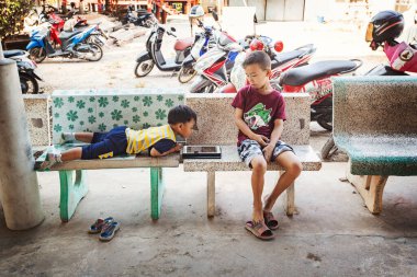 Taylandlı çocuklar Bangkok, Tayland 'da tabletle oynuyorlar.