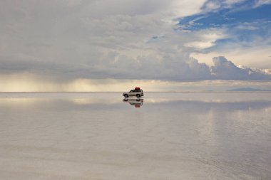 UYUNI, BOLIVIA - Şubat 2020: Uyuni Salt Lake, Bolivya 'nın muhteşem manzarası. Salar de Uyuni 'deki Offroad arabası tuz gölü, Bolivya