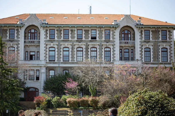 İSTANBUL, TURKEY - Nisan 2021: İstanbul 'daki Boazii Üniversitesi' nde kampüs binası. Güneşli bir günde çimenlerde oturan hindi öğrenciler