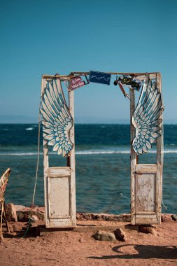 DAHAB, EGYPT - Ekim 2020: Dahab 'daki deniz kenarındaki kafede yaratıcı dekorasyon: denizin önündeki eski ahşap kapılar ve kanatlar, Dahab, Mısır