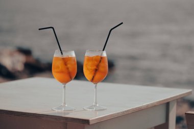 İki Aperol Spritz kokteyli denizin önündeki masada.