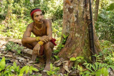 SIBERUT, INDONEZYA - 5 Kasım 2025: Geleneksel giysi ve vücut dekorasyonları giyen Mentawai şamanı geleneksel bir avcı kıyafeti Siberut Sumatra Endonezya ile ormanda avlanıyor