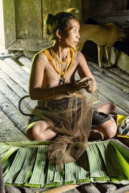 SIBERUT, INDONESIA - 5 Kasım 2025: Yaşlı Mentawai kabilesinden palmiye ağacı eteği ve boncuklu kadın Sibirur adası Batı Sumatra Endonezya 'da balık tutmaya hazırlanıyor