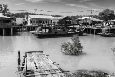 PALAU KETAM, MALAYSIA - 30 Kasım 2025: Malezya 'nın barışçıl kıyı köyü Pulau Ketam' daki ahşap evlerin yanında demirli geleneksel balıkçı tekneleri