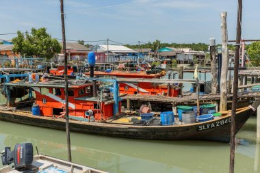 PULAU KETAM, MALAYSIA - 30 Kasım 2025: Malezya 'nın barışçıl kıyı köyü Pulau Ketam' da ahşap evlerin yanında demirli geleneksel balıkçı tekneleri