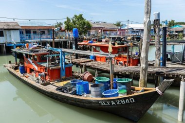 PULAU KETAM, MALAYSIA - 30 Kasım 2025: Malezya 'nın barışçıl kıyı köyü Pulau Ketam' da ahşap evlerin yanında demirli geleneksel balıkçı tekneleri