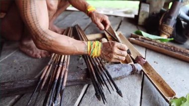 SIBERUT, INDONEZYA - 15 Kasım 2025: Geleneksel giysi ve vücut dekorasyonlarıyla Mentawai şamanı zehri Siberut Adası 'ndaki Sibirya Sumatra Endonezya' daki evinde avlanmak için hazırlıyor.