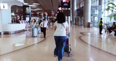 SINGAPORE - 10 Nisan 2025: Havaalanında bayram için giden bagaj vagonunu iten kadın