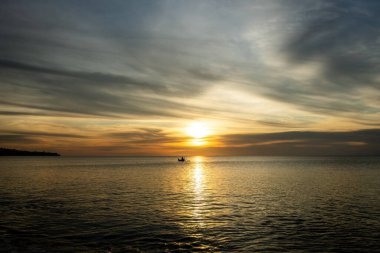 Bali 'de nefes kesici gün batımı. Dalgalı okyanuslara ve palmiye ağaçlarına karşı parlak gün doğumu gökyüzü, Bali, İndinezya