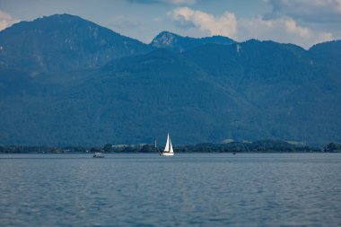 Almanya, Bavyera 'da göl ve dağ manzarası. Suyun üzerinde beyaz yelkenli