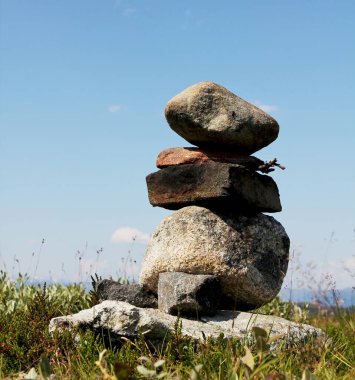 Dengede duran bir yığın taş. Taşlar pürüzlü ve yığın bir çim tarlasında duruyor.