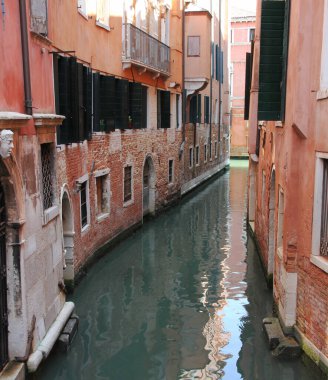 Venedik 'te bir kanal caddesi. Etrafı yüksek eski evlerle dolu dar bir su yolu.. 