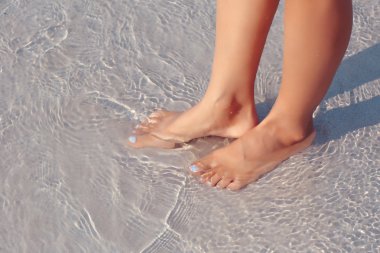 Female feet in water on the beach