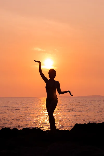 Silueta de mujer de pie en pose de yoga sobre fondo de mar retroiluminado — Foto de Stock