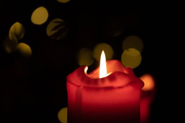 Kırmızı yuvarlak mum arka planda Bokeh ışıkları yanıyor.