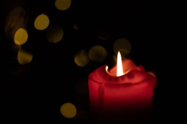 Kırmızı yuvarlak mum arka planda Bokeh ışıkları yanıyor.