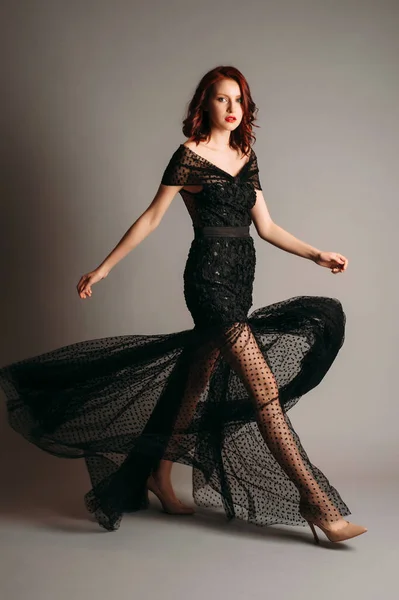 Black transparent long evening dress. Beautiful slim bending model wearing high heels, modern feminine look for an event. Women\'s fashion. Adorable lady.