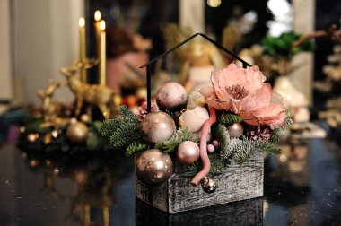 Mutlu Noel kompozisyonu. Noel topları, köknar ağacı dalları, siyah arka planda şenlikli mumlar olan çiçek buketi. Tatil konsepti. Mutlu yeni yıl dekorasyonları.