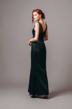 Yeşil, uzun gece elbisesi. Yüksek topuklu ayakkabı giyen güzel bir manken, modern kadınsı bir etkinlik arıyor. Kadın modası. Sevimli bayan..