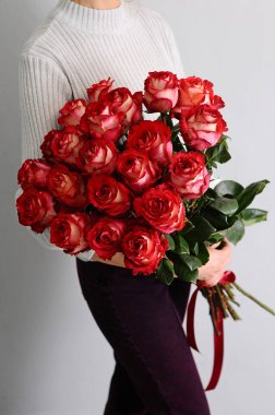 Bir buket kırmızı gül. Sevgililer günü için hediye fikri. Çiçekçi kadın elinde büyük taze bir buket tutuyor. Bir demet 20 uzun çiçeğin hediyesi..