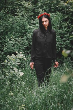 Gözleri siyah giysiler içinde ve arka planda kırmızı küpeler takmış güzel bir kız.